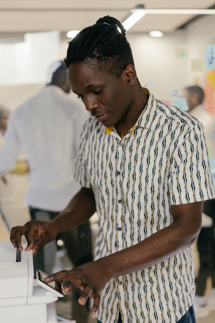 Focused man using a photocopier in a modern office setting.